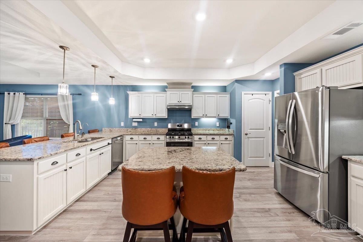 7191 Apples Way Navarre, FL 32566 - Photo 28 of 54 a large kitchen with stainless steel appliances granite countertop a stove a sink dishwasher a refrigerator white cabinets with wooden floor