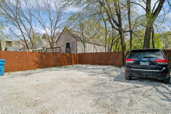 a view of backyard with wooden fence and large trees