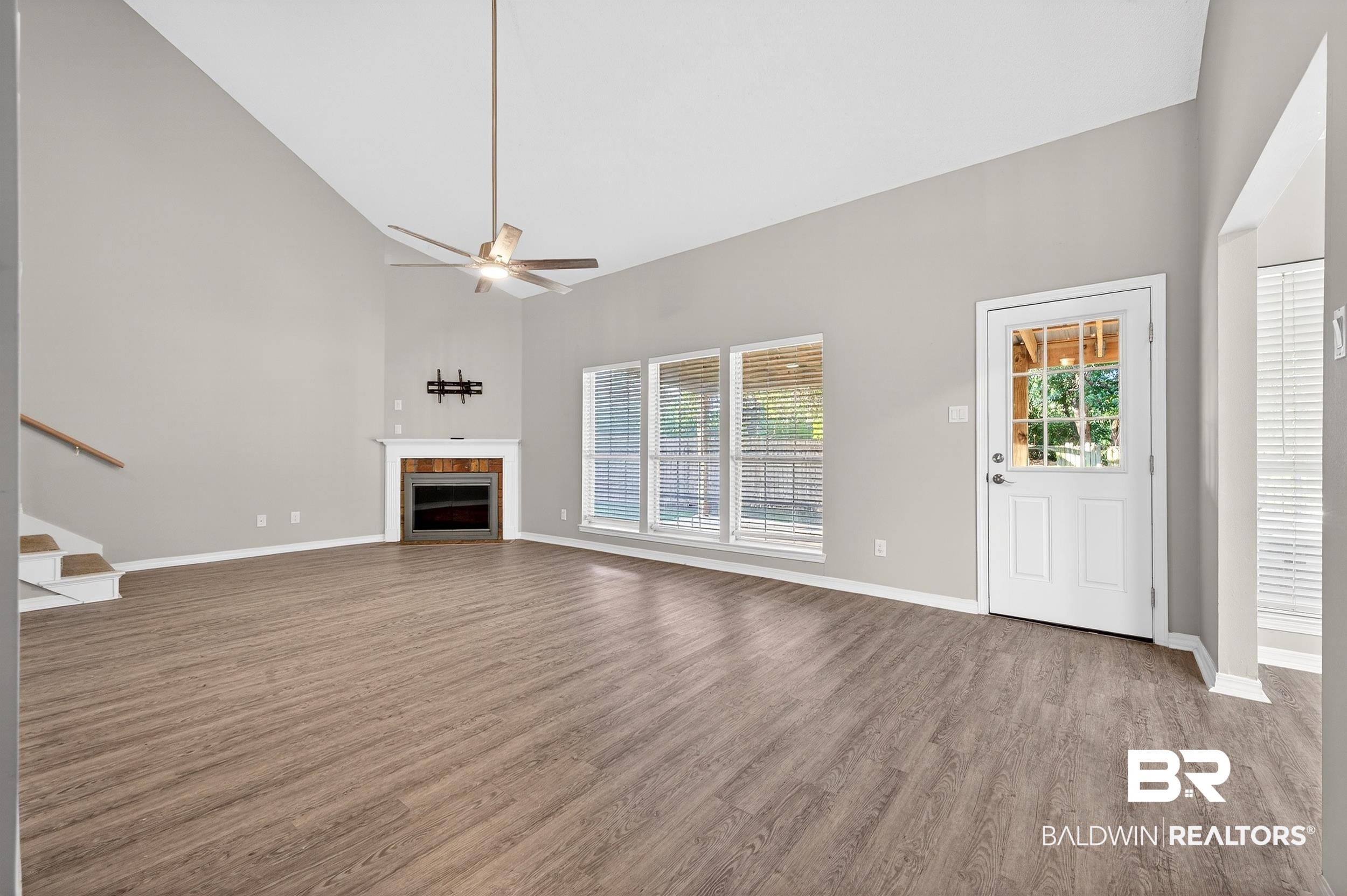 7050 Highpointe Place West Daphne, AL 36527 - Photo 30 of 66 Unfurnished living room featuring dark wood-style flooring, vaulted ceiling, a fireplace, and a ceiling fan