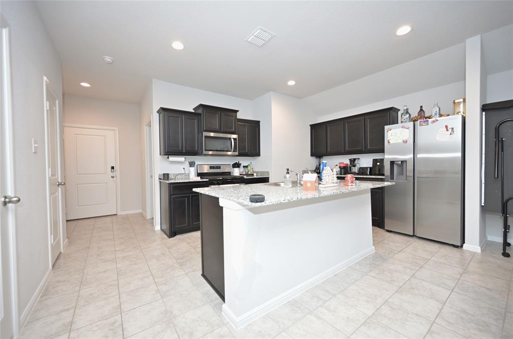 3713 Ridgeway Lane Argyle, TX 76226 - Photo 3 of 40 a kitchen with stainless steel appliances a refrigerator stove microwave and sink