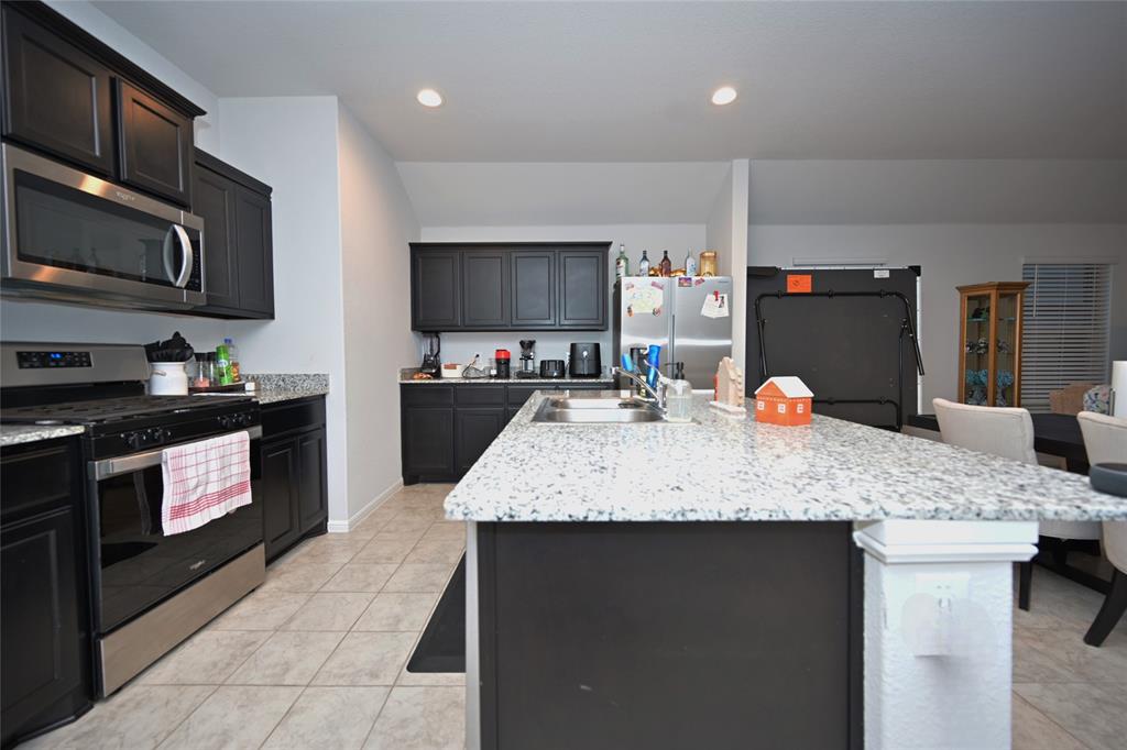 3713 Ridgeway Lane Argyle, TX 76226 - Photo 4 of 40 a kitchen with stainless steel appliances granite countertop a sink a stove top oven a granite counter space and cabinets