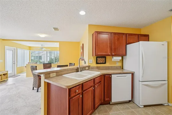 a kitchen with a refrigerator a stove a sink and a dining table with wooden floor