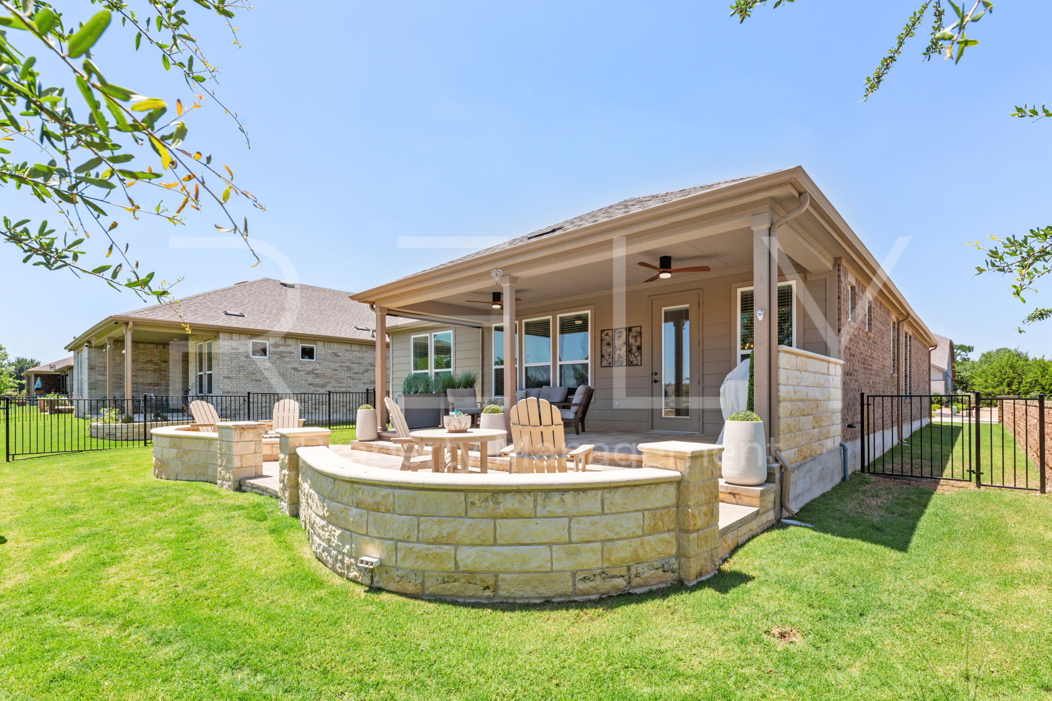 101 Spanish Star Street Georgetown, TX 78633 - Photo 37 of 39 An inviting backyard patio features a stone retaining wall and an open-air fire pit.