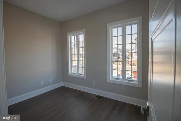 an empty room with wooden floor closet and windows