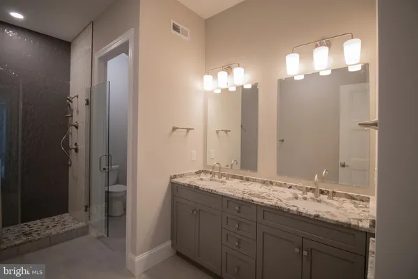 a bathroom with a granite countertop sink a shower and a mirror