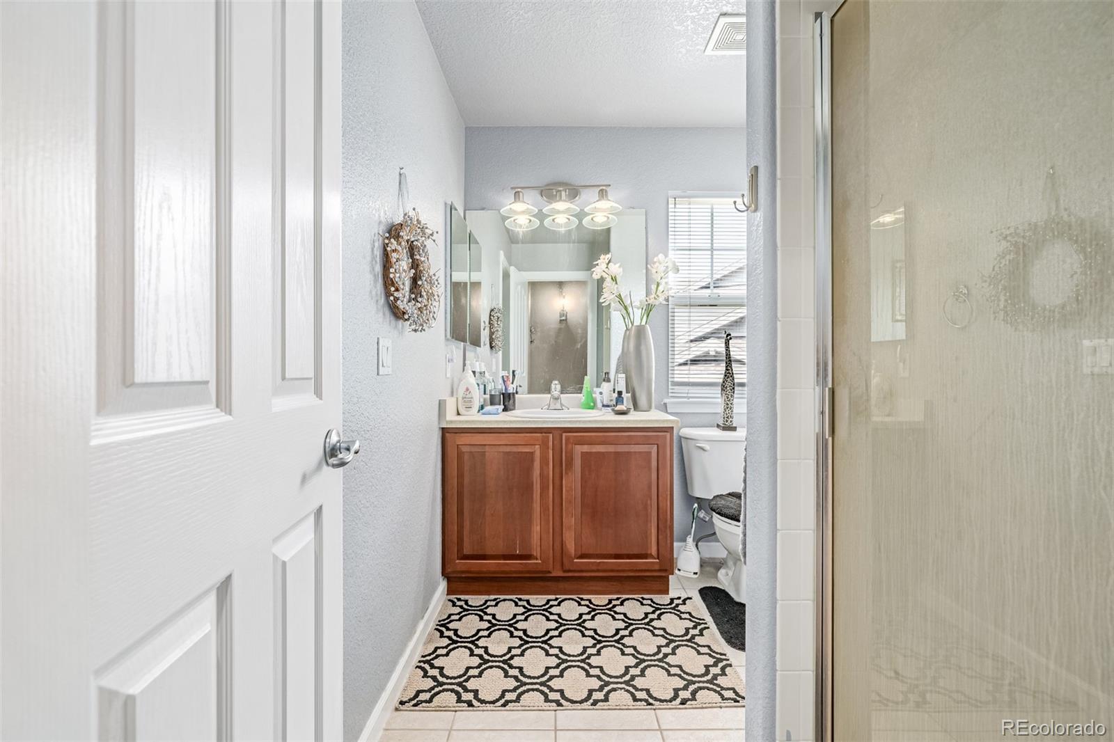24248 East Roxbury Circle Aurora, CO 80016 - Photo 11 of 42 a bathroom with a mirror and a shower