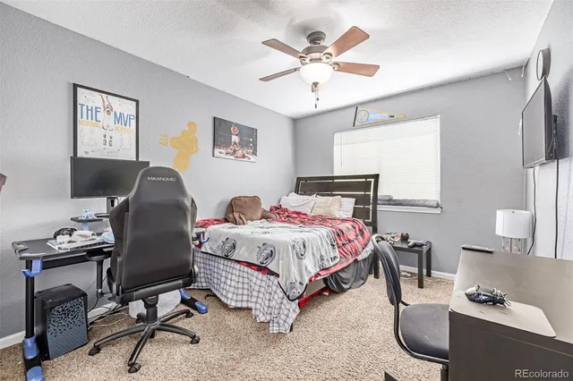 a bedroom with a bed a desk chair and a chandelier