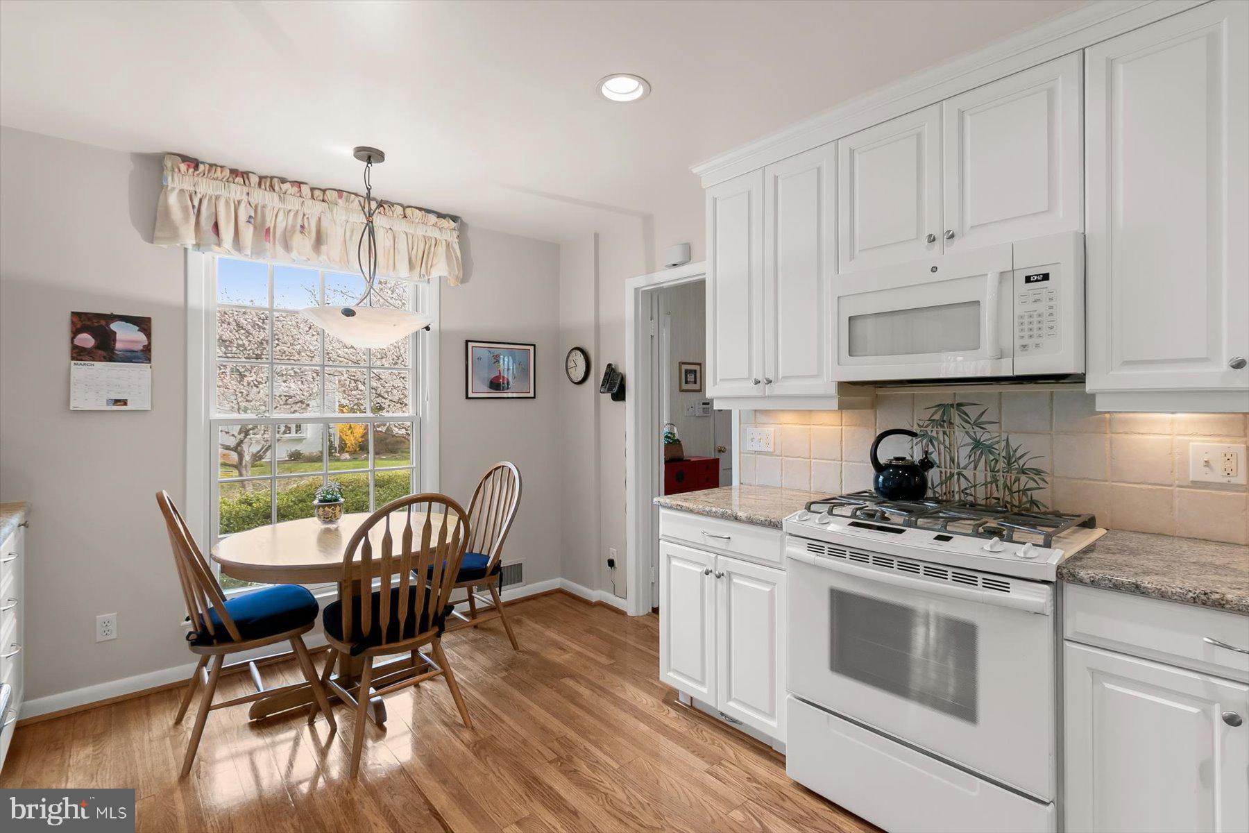 4716 Merivale Road Chevy Chase, MD 20815 - Photo 14 of 48 a kitchen with stainless steel appliances a white table chairs and a wooden floor