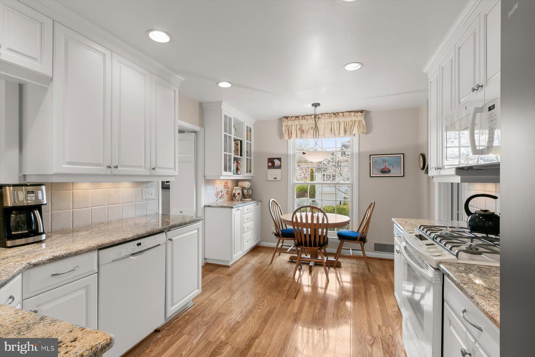 4716 Merivale Road Chevy Chase, MD 20815 - Photo 15 of 48 a kitchen with stainless steel appliances granite countertop a stove top oven a sink dishwasher and white cabinets with wooden floor