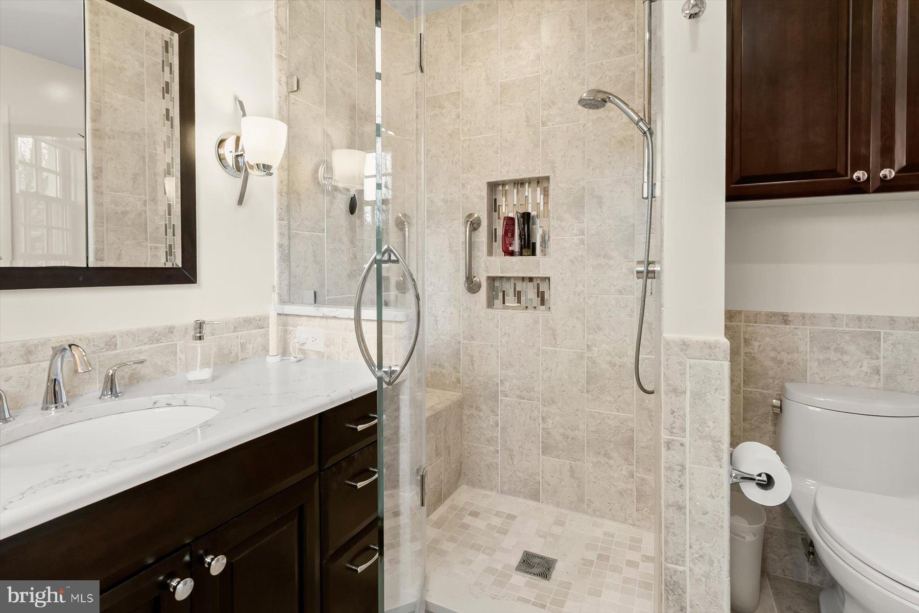 4716 Merivale Road Chevy Chase, MD 20815 - Photo 28 of 48 a bathroom with a granite countertop sink a toilet a mirror and shower