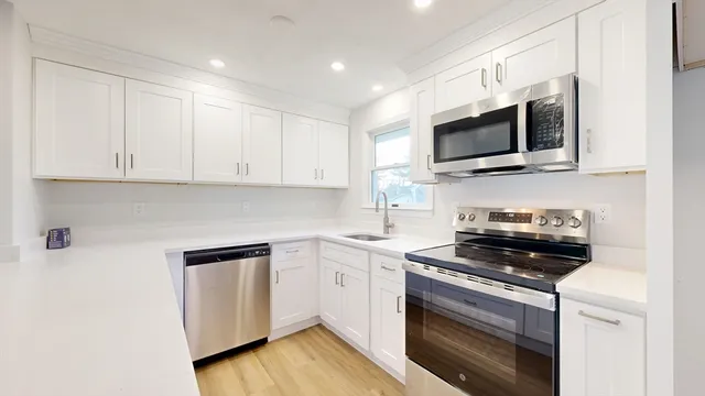 a kitchen with stainless steel appliances granite countertop a stove a microwave and white cabinets