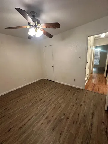 an empty room with wooden floor and fan