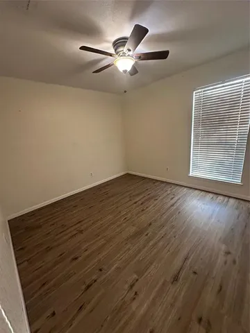 an empty room with wooden floor fan and windows