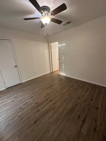 an empty room with wooden floor and a ceiling fan