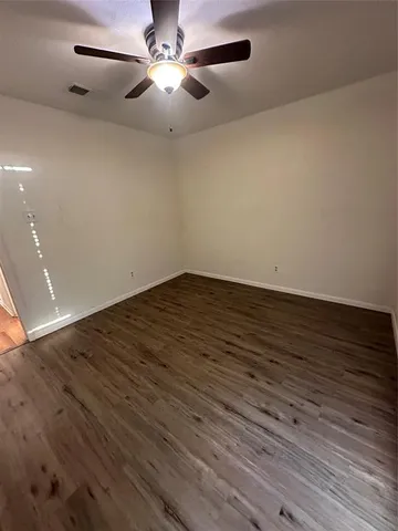 an empty room with wooden floor fan and window