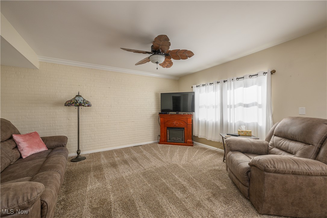 1320 Perry Drive Northwest Canton, OH 44708 - Photo 6 of 34 Living room featuring ceiling fan, carpet flooring, ornamental molding, a fireplace, and brick wall