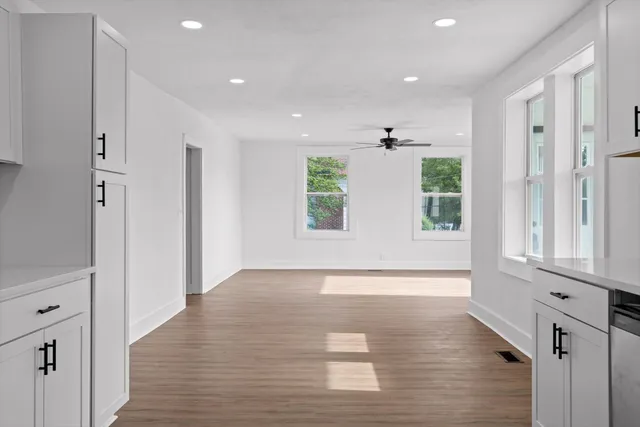 a view of an empty room with wooden floor and a window
