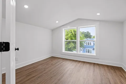 an empty room with wooden floor and window