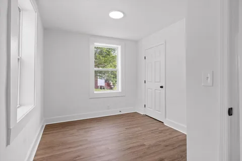 an empty room with wooden floor and window