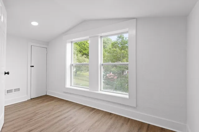 an empty room with wooden floor and windows