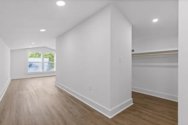 a view of an empty room with wooden floor and a window