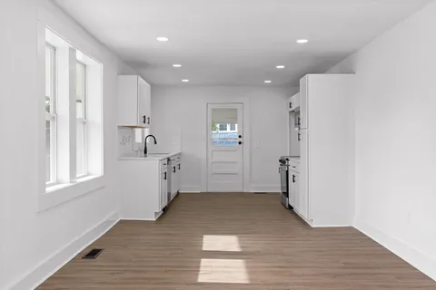 a view of empty room with wooden floor and window