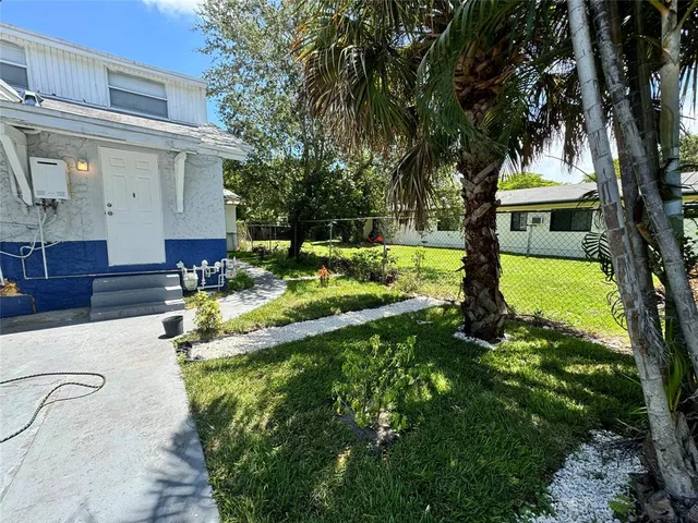 a view of a house with a yard patio and a tree