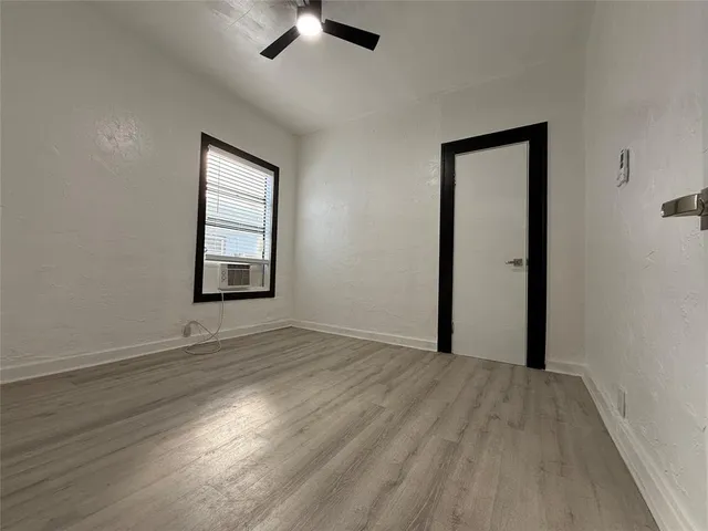 an empty room with wooden floor cabinet and windows