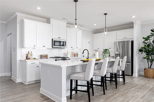 a kitchen with stainless steel appliances kitchen island granite countertop a dining table chairs and white cabinets