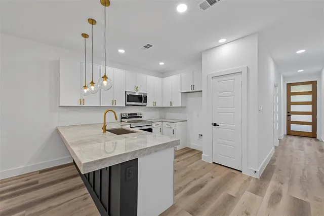 a kitchen with white cabinets sink and stainless steel appliances