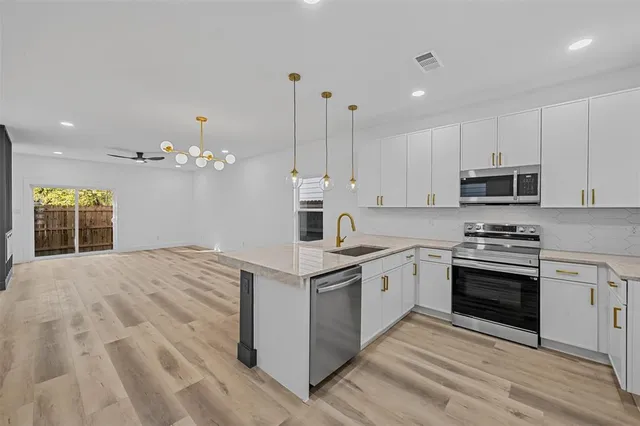 a kitchen with stainless steel appliances granite countertop a stove top oven a sink dishwasher and a refrigerator