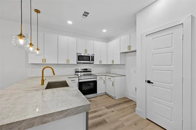 a kitchen with kitchen island granite countertop a sink stainless steel appliances and white cabinets