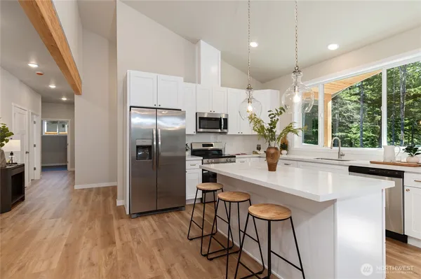 a kitchen with stainless steel appliances granite countertop a refrigerator a sink dishwasher a stove and a microwave oven with wooden floor