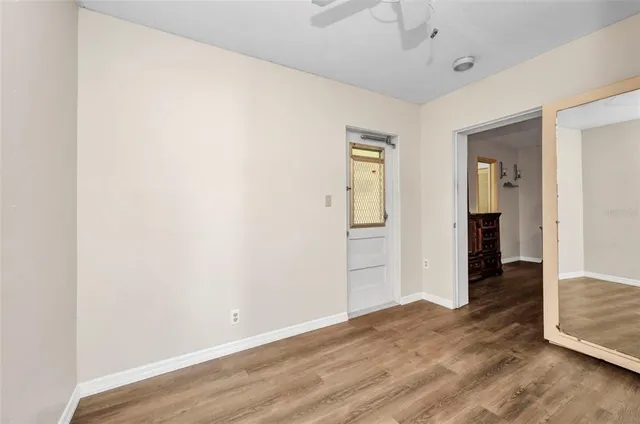 an empty room with wooden floor and bathroom