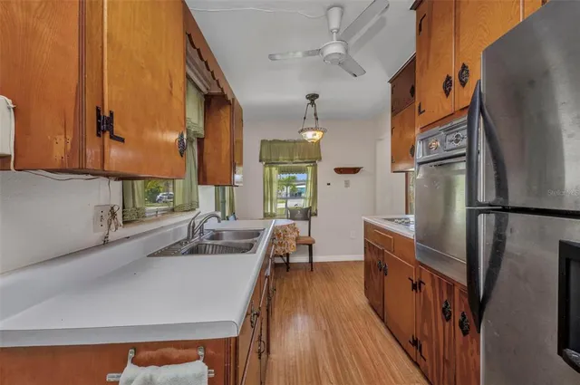 a kitchen with refrigerator a stove and a sink with wooden floor