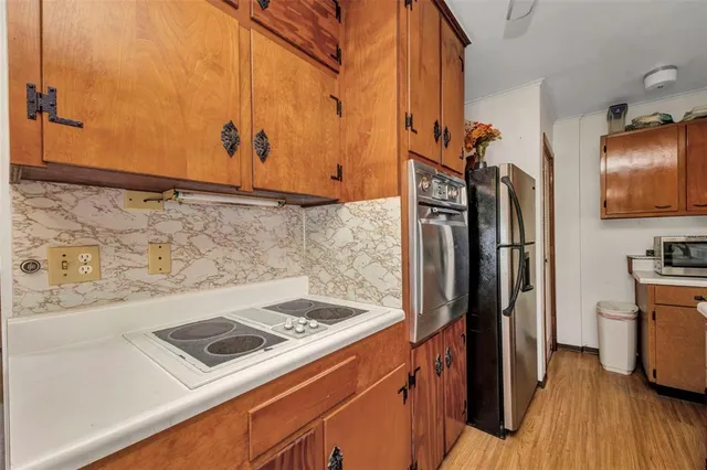 a kitchen with stainless steel appliances granite countertop a refrigerator a stove and a sink with wooden floor