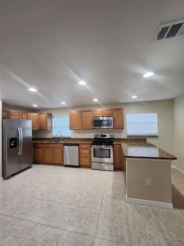 a large kitchen with stainless steel appliances granite countertop a stove granite counter tops and white cabinets