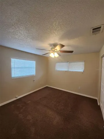 an empty room with a fan & a window