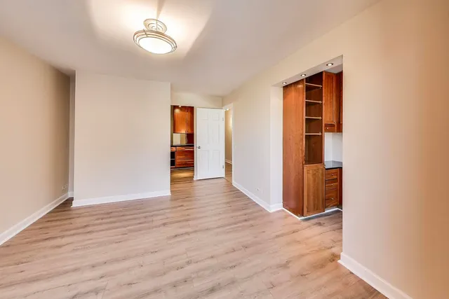 an empty room with wooden floor closet and windows