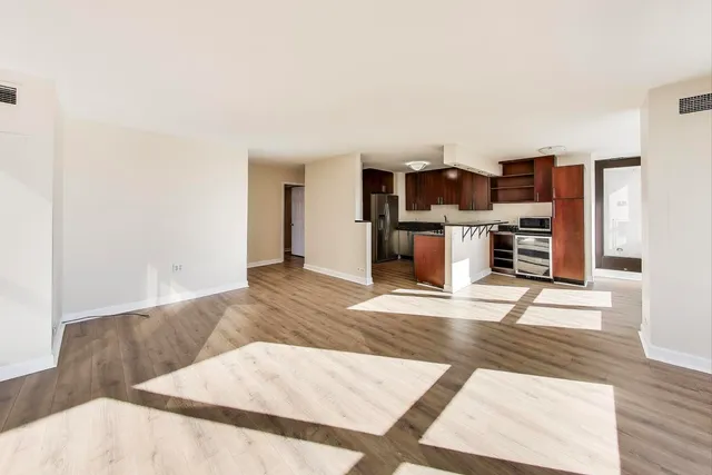 a living room with stainless steel appliances kitchen island hardwood floor and a fireplace