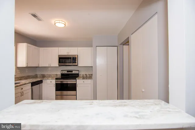 a kitchen with stainless steel appliances granite countertop a stove top oven a sink and a refrigerator