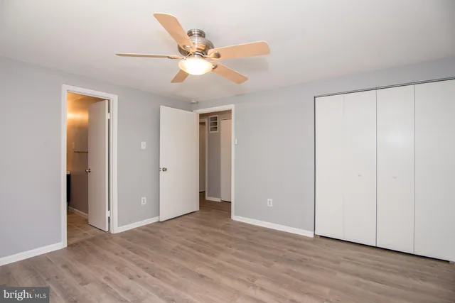 an empty room with wooden floor fan and windows