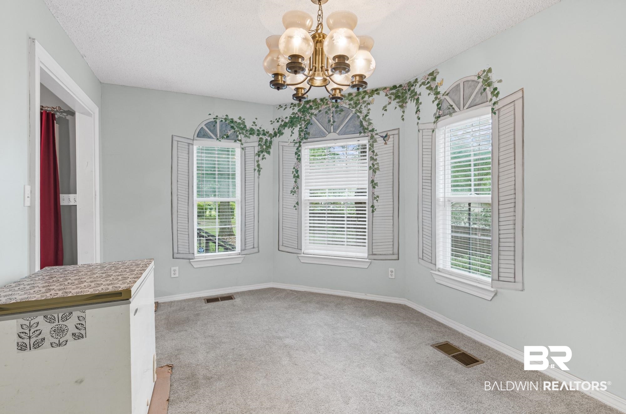 8675 Hunters Pointe Drive North Theodore, AL 36582 - Photo 9 of 20 Room featuring a classic brass chandelier, three windows with blinds, and light-colored carpeting