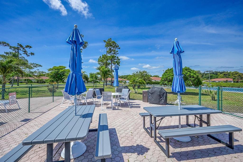 5245 Northwest 3rd Street, Unit D Delray Beach, FL 33445 - Photo 14 of 18 a view of a patio with table and chairs potted plants and palm tree