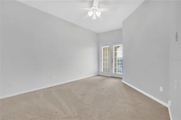 an empty room with a chandelier fan and windows