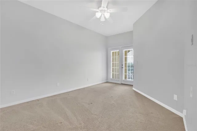 an empty room with a chandelier fan and windows