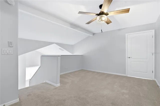 an empty room with chandelier fan and windows