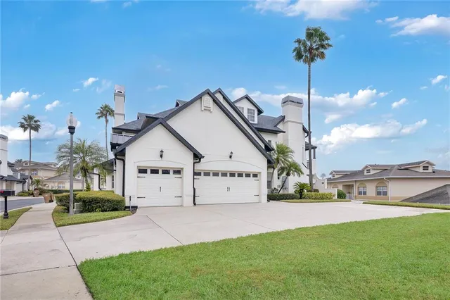a view of a white house next to a yard with a fountain
