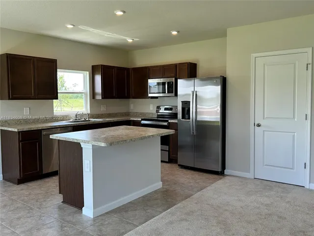 a kitchen with stainless steel appliances granite countertop a stove top oven a refrigerator and a sink