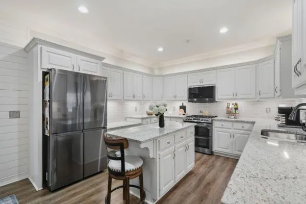 a kitchen with a refrigerator a sink dishwasher a stove and white cabinets with wooden floor